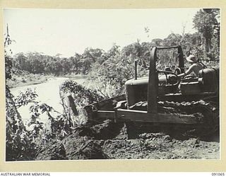 BOUGAINVILLE. 1945-04-21. A BULLDOZER PUSHING TOPSOIL INTO THE PURIATA RIVER DURING THE CONSTRUCTION OF A ROAD CAPABLE OF HANDLING 3-TON VEHICLES BY 15 FIELD COMPANY ROYAL AUSTRALIAN ENGINEERS. IT ..