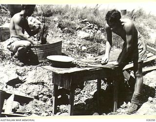 NEW GUINEA, 1942-08. WASHING DAY IN NEW GUINEA. AUSTRALIAN SOLDIERS RUBBING AND SCRUBBING THEIR SHIRTS AND SHORTS