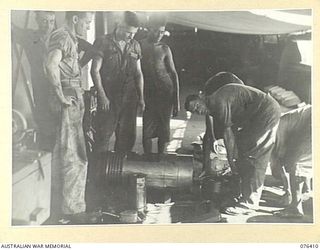 LABU, NEW GUINEA. 1944-10-03. MARINE ENGINEERS OF THE 1ST WATERCRAFT WORKSHOPS, FITTING A CONNECTING ROD TO ONE OF THE PISTONS OF THE ENGINE OF THE "FRANCES PEAT", SUPERVISED BY NX23747 LIEUTENANT ..