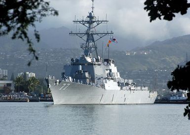 A port bow view of the US Navy (USN) Arleigh Burke Class (Flight IIA) Guided Missile Destroyer (AEGIS), USS OKANE (DDG 77) showing her crew manning the rails as she departs Pearl Harbor, Hawaii (HI), as part of a regularly scheduled around the world deployment with the USN Nimitz Class Aircraft Carrier, USS CARL VINSON (CVN 70) Carrier Strike Group (CSG)