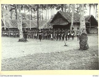 MILNE BAY, NEW GUINEA. 1944-04-20. GUARDS FROM THE ROYAL PAPUAN CONSTABULARY, (AT THE FOREGROUND), STAND ALONGSIDE PRISONERS IN THE BARAGA NATIVE LABOUR CAMP. THE PRISONERS, (INCLUDING MANY ..