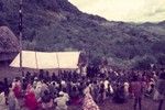 Patrol officer (center, in red cap) with his translator addresses villagers, Australian flag on pole at left