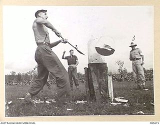 HERBERTON RACECOURSE, WONDECLA, ATHERTON TABLELAND, QLD. 1945-01-19. PRIVATE S GRAY, 2/15 INFANTRY BATTALION (1), COMPETING IN THE WOODCHOP EVENT DURING THE 9 DIVISION GYMKHANA. ALONGSIDE STANDS ..