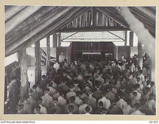 LAE, NEW GUINEA, 1945-05-09. THE CONGREGATION STANDING TO ATTENTION DURING THE PLAYING OF A RECORDING OF THE NATIONAL ANTHEM AT THE THANKSGIVING SERVICE CONDUCTED BY CHAPLAIN E.M. WATTS AT 112 ..