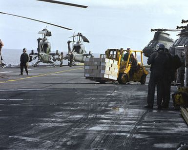 AH-1T Sea Cobra helicopters and CH-46 Sea Knight helicopters line the flight deck as a forklift operator moves cargo aboard the amphibious assault ship USS GUAM (LPH-9), stationed off the coast of Beirut. The ship is providing support to U.S. Marines deployed in Lebanon as part of a multi-national peacekeeping force following confrontation between Israeli forces and the Palestine Liberation Organization