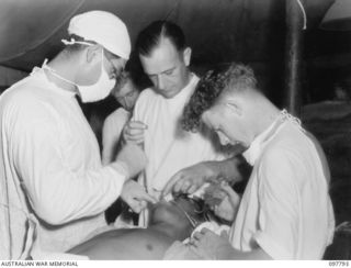 RABAUL, NEW BRITAIN, 1945-10-08. CAPT W.J. STONEY, DENTAL SECTION, 105 CASUALTY CLEARING STATION, PACKING GAUZE INTO AND AROUND TUBE IN PATIENT'S THROAT TO PREVENT HIS BREATHING THROUGH HIS MOUTH ..