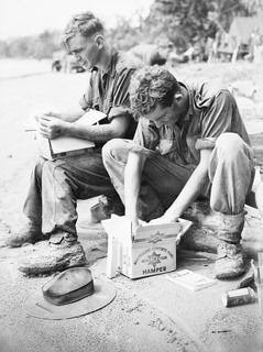 WEWAK AREA, NEW GUINEA, 1945-07-05. LANCE-CORPORAL A.N. BRODERICK (1) AND PRIVATE R. COULHARD (2) FORWARD TROOPS OF HEADQUARTERS 6 DIVISION DELVE INTO THE MID-YEAR HAMPERS PROVIDED BY THE ..