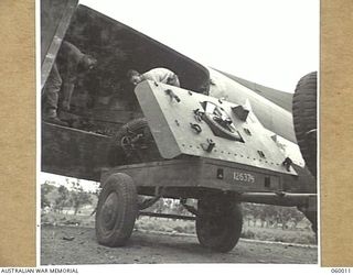 PORT MORESBY, NEW GUINEA. 1943-11-15. TROOPS OF THE 2/5TH AUSTRALIAN FIELD REGIMENT UNLOADING THE PARTS OF A SHORT 25-POUNDER GUN FROM A DOUGLAS AIRCRAFT, ON TO A TRAILER, DURING THE UNIT'S ..