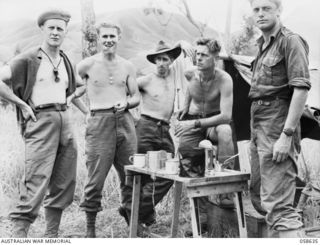 RAMU VALLEY, NEW GUINEA, 1943-10-03. MESS TIME AT HEADQUARTERS 2/7TH AUSTRALIAN INDEPENDENT COMPANY. LEFT TO RIGHT:- NX70117 LIEUTENANT W.R. TOOLE; VX38184 CAPTAIN F.J. LOMAS, OFFICER COMMANDING; ..