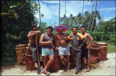 Group of men standing by oil drums, Mauke