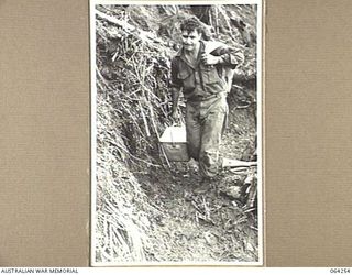 FINISTERRE RANGES, NEW GUINEA. 1944-01-23. QX8034 PRIVATE A.V. ABBOTT, OF THE 2/9TH INFANTRY BATTALION CARRYING DIXIES OF FOOD TO FORWARD TROOPS ON SHAGGY RIDGE