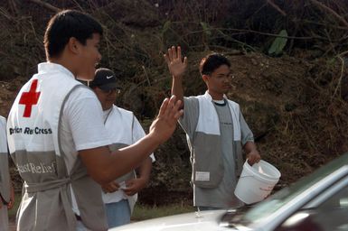 Red Cross volunteers wave and thank morning rush hour traffic for their donations along Marine Drive in Agana, Guam, that will help victims of Super Typhoon Paka