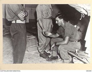 JACQUINOT BAY, NEW BRITAIN. 1945-04-08. SHARING A NEWSPAPER CUTTING, SENATOR J.M. FRASER, ACTING MINISTER FOR THE ARMY (1), AND PRIVATE A.R. TALBOT (2), COMPARE THE SITUATION IN THE EUROPEAN ..