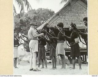 MENDAROPU, NEW GUINEA. 1942-10. P391 CAPTAIN B.W. FAITHORN, AUSTRALIAN AND NEW GUINEA ADMINISTRATION UNIT INSPECTING THE RIFLES OF MEMBERS OF THE ROYAL PAPUAN CONSTABULARY