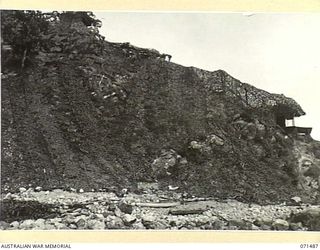 PORT MORESBY, PAPUA. 1944-03-27. THE CAMOUFLAGED COMMAND POST AT PAGA BATTERY, COAST ARTILLERY VIEWED FROM THE BEACH. THE BATTERY, EQUIPPED WITH A SEARCHLIGHT AND TWO SIX INCH GUNS, OVERLOOKS AN ..