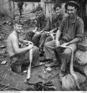1942-12-16. PAPUA. FALL OF GONA. THESE DIGGERS WERE THE GUN-CREW WHICH KILLED 18 JAPS. AS THE JAPANESE TRIED TO RUSH OUT OF GONA. THEY ARE LOADING UP MACHINE-GUN BELTS IN READINESS FOR THE JAP'S ..