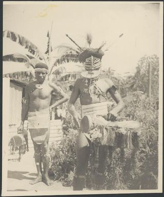 Two male dancers, one wearing a mask and both holding fringed hand drums, Awar Plantation, Sepik River, New Guinea, 1935 / Sarah Chinnery