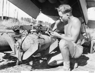 MILNE BAY, PAPUA. 1943-07-21. CORPORAL J. T. BIGNALL, NEWCASTLE, NSW, ARMOURER, PREPARING THE BOMB LOAD FOR A BEAUFORT BOMBER AIRCRAFT OF NO. 100 SQUADRON RAAF