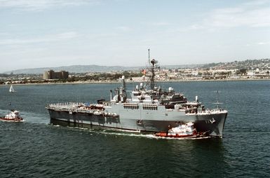 Crew members man the rails aboard the miscellaneous flagship USS CORONADO (AGF-11) as commercial harbor tugs maneuver the vessel toward port at Naval Air Station, North Island. The CORONADO, flagship for Commander, Third Fleet, is entering its new home port after being stationed in Hawaii for almost 20 years