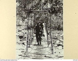 FARIA VALLEY, NEW GUINEA. 1944-02-10. NX103242 GUNNER C.F. COSTELLO, OF THE 11TH FIELD BATTERY, 4TH FIELD REGIMENT, CROSSING THE FARIA RIVER NEAR GUY'S POST ON A ROPE SUSPENSION BRIDGE IN THE ..