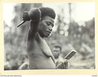 KAMALGAMAN ANCHORAGE, NEW BRITAIN. 1944-12-31. A NATIVE WOMAN DOING HER HAIR BEFORE PARTICIPATING IN THE SING-SING AT THE AUSTRALIAN AND NEW GUINEA ADMINISTRATIVE UNIT HEADQUARTERS