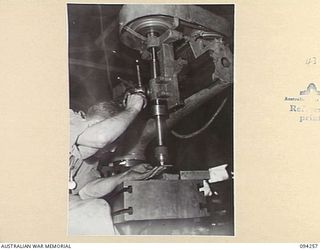 PALMALMAL PLANTATION, NEW BRITAIN. 1945-07-21. CRAFTSMAN T. CASTLES OPERATING A RADIAL DRILL IN THE POWER MACHINE SECTION OF 1 INFANTRY TROOPS WORKSHOP. IN THE UNIT ALL PARTS FROM JEEPS ARE ..