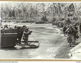 LANGEMAK BAY, NEW GUINEA, 1943-10-28. MEMBERS OF THE 2/24TH AUSTRALIAN INFANTRY BATTALION BOARDING BARGES AT THE BEACHHEAD. SHOWN ARE:- VX48636 MAJOR H.W. SNELL (2); VX34090 WARRANT OFFICER II. ..