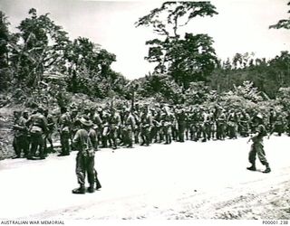 THE SOLOMON ISLANDS, 1945-09-19. JAPANESE TROOPS FROM NAURU ISLAND, UNDER AUSTRALIAN GUARDS, PAUSE FOR A REST BY THE ROADSIDE ON THEIR MARCH FROM TOROKINA TO AN INTERNMENT CAMP ON BOUGAINVILLE ..