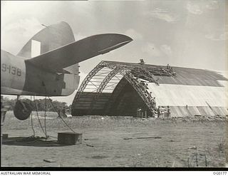 VIVIGANI, GOODENOUGH ISLAND, PAPUA NEW GUINEA. 1943-09-23. LOOKING PAST THE TAIL OF A BEAUFIGHTER AIRCRAFT, A19-138, OF NO. 30 SQUADRON RAAF, TOWARDS AN "IGLOO" HANGAR UNDER CONSTRUCTION BY NO. 7 ..