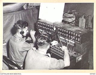 RABAUL, NEW BRITAIN. 1945-09-23. SIGNALMAN J. SINCLAIR (1) AND SIGNALMAN J.A. LEE (2), MEMBERS OF 11 DIVISION SIGNALS, OPERATING THE SWITCHBOARD IN THE ORIGINAL SIGNAL OFFICE AT HEADQUARTERS 11 ..