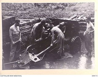 BOUGAINVILLE. 1945-07-19. GUN CREWS OF 6 FIELD BATTERY, 2 FIELD REGIMENT, ROYAL AUSTRALIAN ARTILLERY, WORKING IN THEIR FLOODED GUN PITS EAST OF THE OGORATA RIVER. DUE TO A SEVEN INCH RAINFALL IN ..