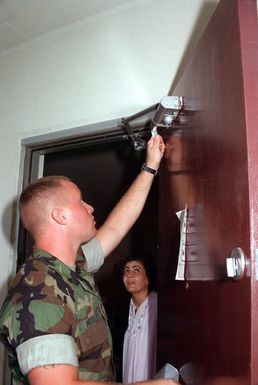 Lance CPL. Jason Moxley, Facilities Maintenance, Combat Service Support Detachment 37, fixes a door stop at an evacuees home