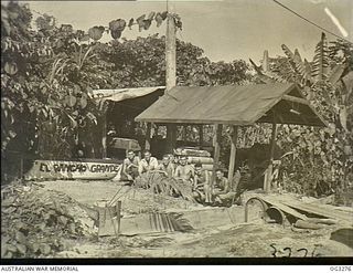 LABUAN, NORTH BORNEO. 1945-08-08. RAAF ARMOURERS OUTSIDE THEIR "BOMBING UP" POINT ON A JUNGLE LANDING AIRSTRIP ON BOUGAINVILLE. NOTE THE HIGH-SOUNDING NAME, EL RANCHO GRANDE, THEY HAVE GIVEN THEIR ..