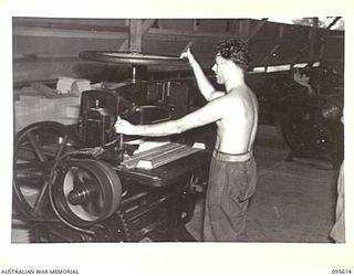 LAE AREA, NEW GUINEA. 1945-08-31. PRIVATE J. WHILEY OPERATING A GUILLOTINE TO CUT PAPER TO PRODUCTION SIZE FOR AN ISSUE OF THE ARMY NEWSPAPER, GUINEA GOLD. THE NEWSPRINT HAS TO BE CAREFULLY STORED ..