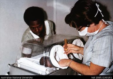 Nurses Leifan and Lois Dickinson in hospital nursery treating baby in humidicrib