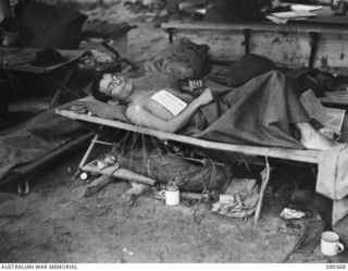 BOUGAINVILLE. 1945-04-06. A JAPANESE PRISONER OF WAR (AN ENGLISH SPEAKING LT) WOUNDED IN ACTION AT SLATER'S KNOLL LYING ON A STRETCHER WITH PRISONER OF WAR TAG ATTACHED, AWAITING REMOVAL TO MAIN ..