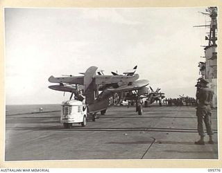 AT SEA OFF RABAUL, NEW BRITAIN. 1945-09-06. BARRACUDA AIRCRAFT BEING TOWED ALONG THE FLIGHT DECK OF THE AIRCRAFT CARRIER HMS GLORY. THE CORSAIRS WILL CIRCLE OVERHEAD DURING THE SURRENDER CEREMONY ..