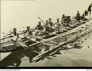 Los Negros Island, Admiralty Group. c. 1943. Fifteen natives moving along in a large outrigger canoe