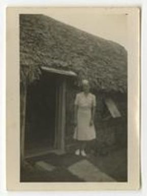 Daphine Doster Mastroianni in front of thatched building