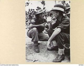 BORAM BEACH, NEW GUINEA. 1945-10-13. SERGEANT E. HAYLETT, A MILITARY MEDAL WINNER OF 2/3 MACHINE-GUN BATTALION (1) AND SERGEANT W.L. REID (2) OF THE SAME UNIT, HAVING A CUP OF TEA BEFORE MOVING ..