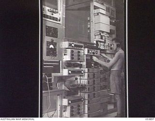 PORT MORESBY, NEW GUINEA. 1943-07-14. VX86697 SIGNALMAN W. DIXON OF THE NEW GUINEA LINES OF COMMUNICATION, SIGNALS, AIF, OPERATING A CS.5 3-CHANNEL CARRIER SYSTEM AND THE 4-CHANNEL TELEGRAPH ..