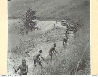 WAU - LAE ROAD, NEW GUINEA, 1944-03-03. THE ROAD 78 MILES FROM WAU. THIRTY SIX CHAINS OF BENCHING WAS CLEARED BY 200 NATIVES UNDER SUPERVISION BY THE AUSTRALIAN NEW GUINEA ADMINISTRATIVE UNIT IN ..