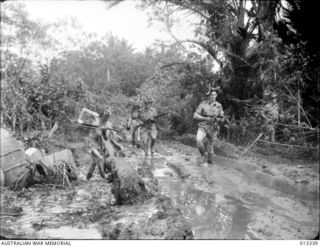 1942-10-01. NEW GUINEA. MILNE BAY. AUSTRALIAN TROOPS PLOUGH THROUGH THE MUD AT MILNE BAY SHORTLY AFTER THE UNSUCCESSFUL JAPANESE INVASION ATTEMPT