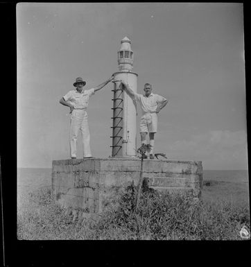 Mr D Ewing (Burns Philp Manager), G Tyrell (Shipping Manager) standing next to a lighthouse in Madang, Papua New Guinea