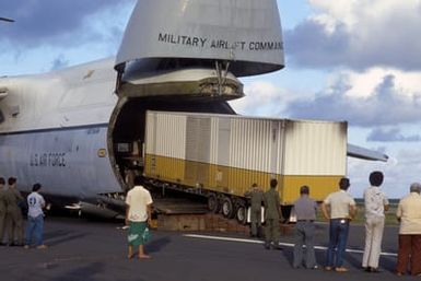 Members of the 22nd Military Airlift Squadron and local Samoans unload a tractor-trailer containing an electrical generator and supplies from the front end of a C-5 Galaxy aircraft at the Pago Pago International Airport