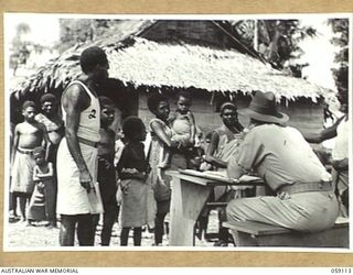 HOPOI, NEW GUINEA, 1943-10-20. NX155085 CAPTAIN R.G. ORMSBY OF THE AUSTRALIAN AND NEW GUINEA ADMINISTRATIVE UNIT, TALKING TO THE NATIVE WOMENFOLK AND CHILDREN, DURING A RECRUITING TRIP