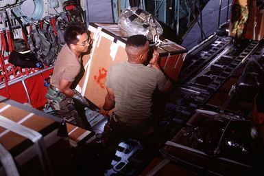 Boxes rigged with parachutes are loaded aboard a 374th Airlift Wing C-130 Hercules aircraft for delivery to islanders of the Federated States of Micronesia. Crews from the 345th and 21st Airlift Squadrons are assigned to fly the C-130 for the Christmas Drop '92 missions. Every Christmas since 1952, food, clothing, tools and toys donated by residents of Guam have been delivered by air to 40 Micronesian islands