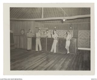 MILNE BAY, PAPUA. OFFICERS POSE AT THE BAR OF THE WARDROOM OF HMAS LADAVA. (NAVAL HISTORICAL COLLECTION)