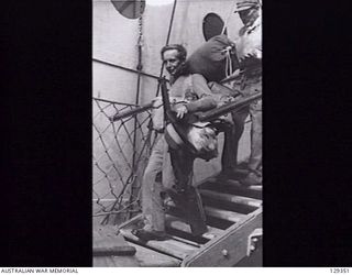 SYDNEY, NSW. 1946-05-16. NX173028 PRIVATE G. MURRAY, 2/60TH INFANTRY BATTALION, STUMBLES DOWN THE GANGPLANK OF THE TROOPSHIP CANBERRA, AFTER IT HAD BERTHED AT CIRCULAR QUAY FROM RABAUL