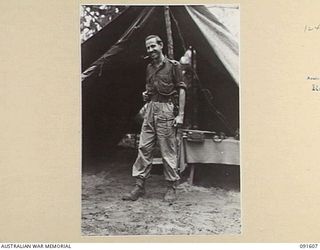 KARAWOP, NEW GUINEA. 1945-05-05. MAJOR B.W.T. CATTERNS, ADMINISTRATIVE COMMANDER, 2/1 INFANTRY BATTALION, ENJOYS A QUIET PIPE OUTSIDE HIS HEADQUARTERS AT THE UNIT'S REAR ECHELON. THEY HAVE NOW ..